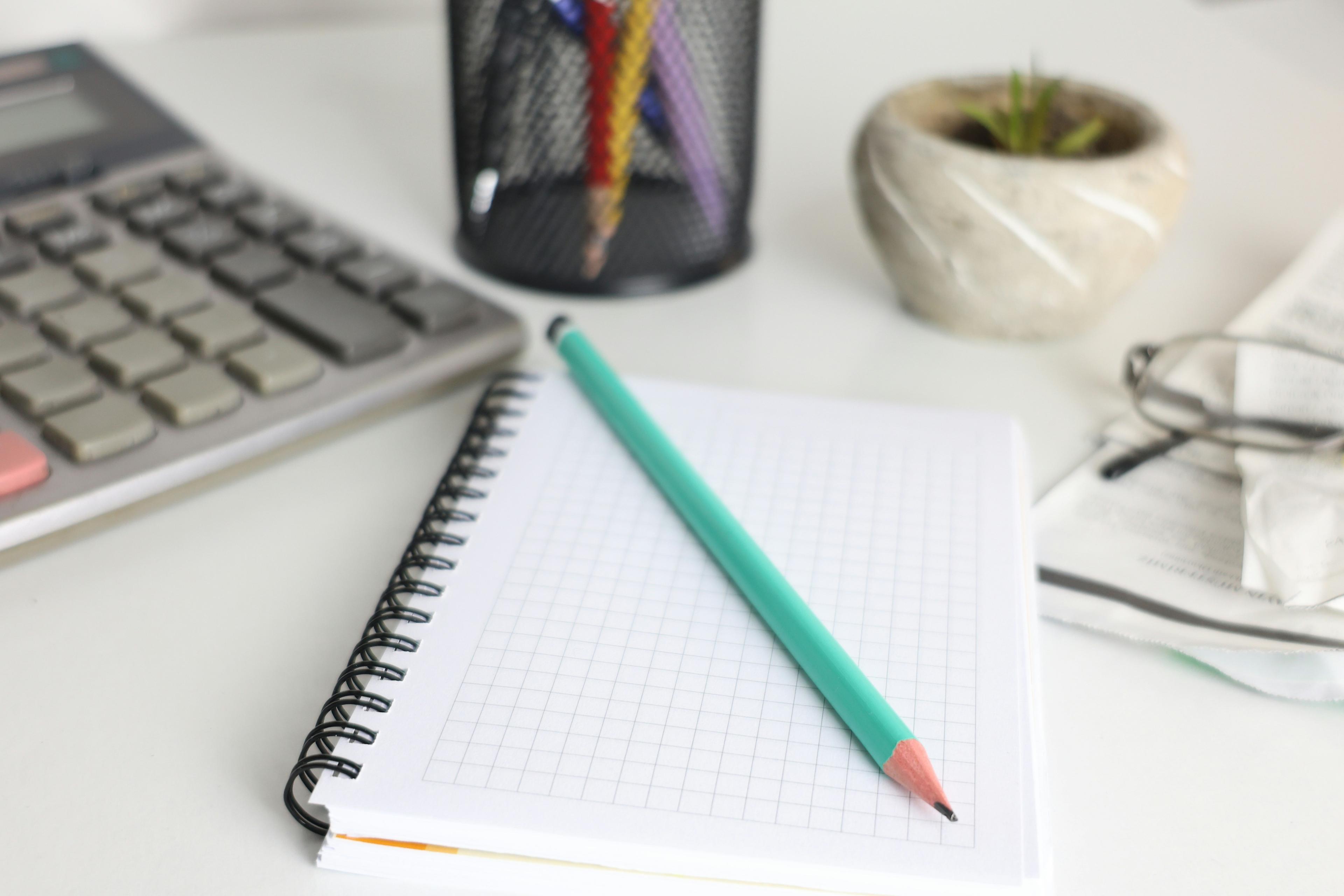 Notebook, pen and calculator on a desk, representing tidy bookkeeping records